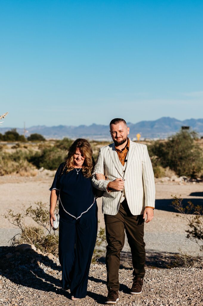 Groom being walked down the aisle by his mother for his Cactus Joe's wedding ceremony on Desert Love Land