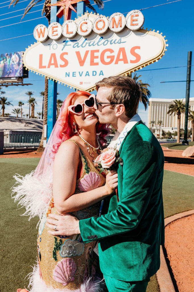 cute picture of the groom kissing the bride at the "welcome to las vegas sign"