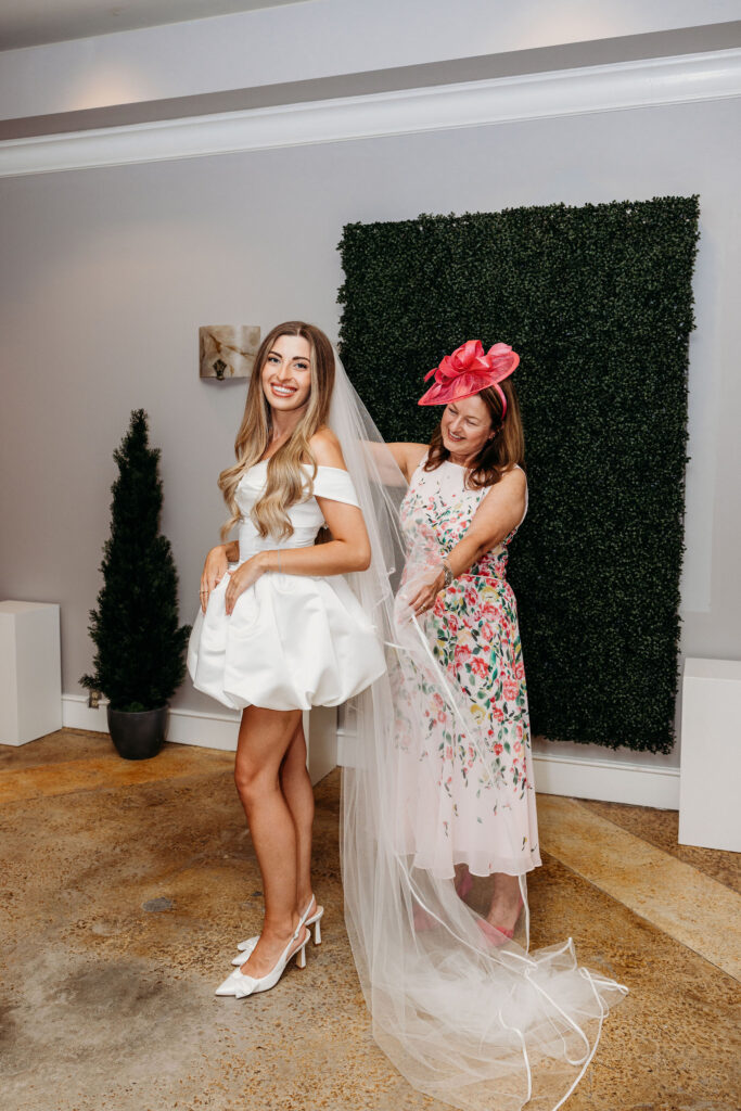 mother of the bride helping her with her wedding dress
